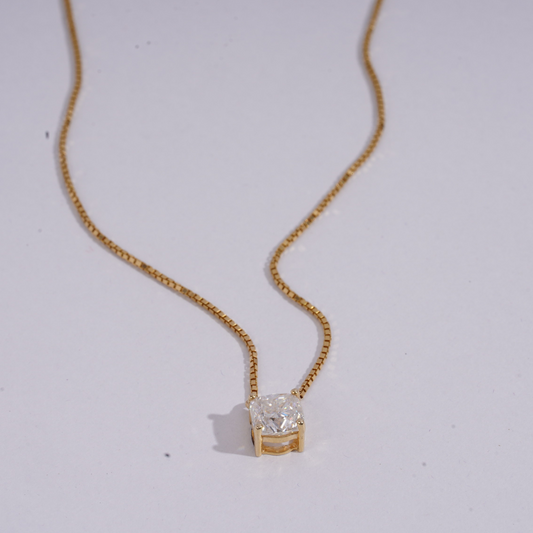 Gold necklace with a diamond pendant on a light gray background