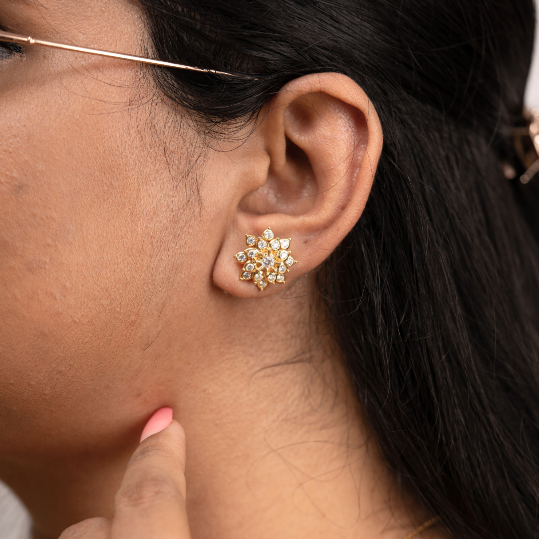 Close-up of a person wearing a gold floral earring.