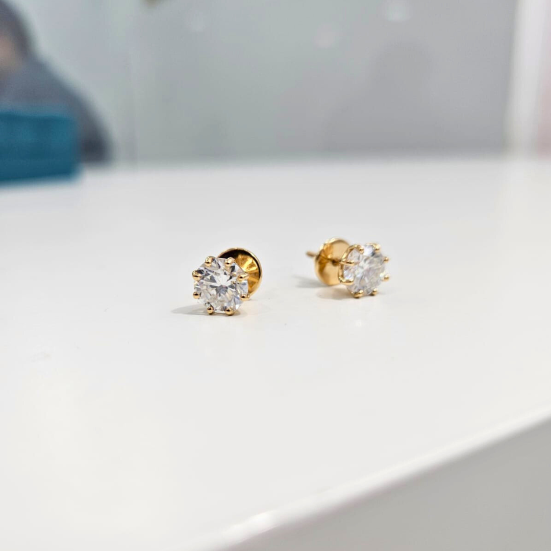 8 prong Gold stud earrings with clear gemstones on a white surface