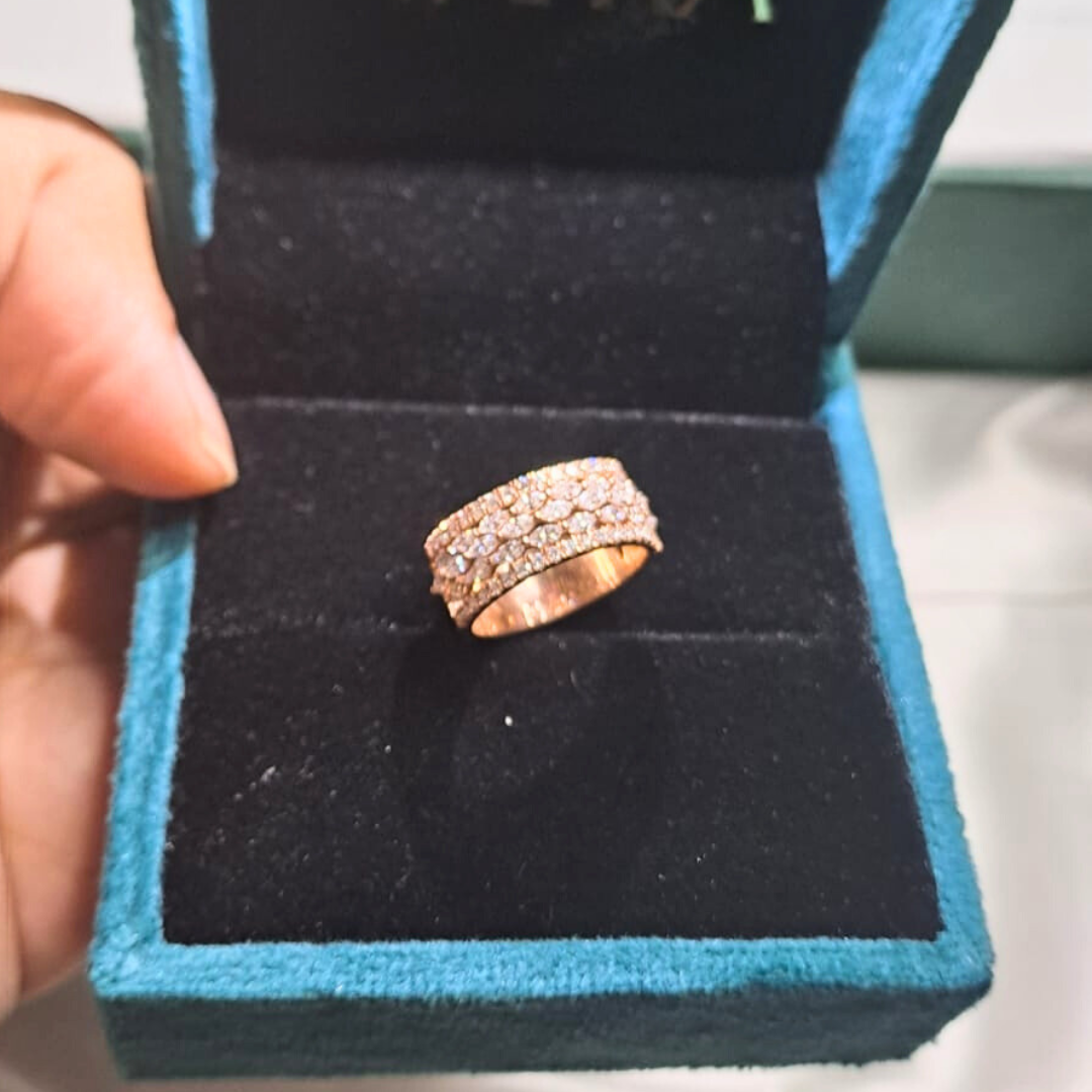 Hand wearing multiple diamond rings on a blurred gray background