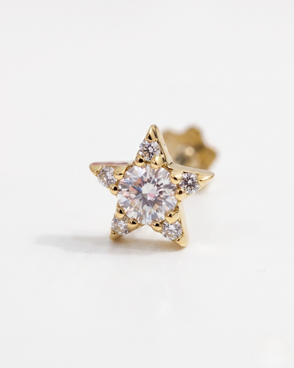Gold star-shaped earring with clear Moissanite gemstone on a white background by Vai Ra for helix piercing
