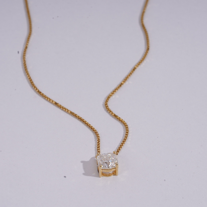Gold necklace with a diamond pendant on a light gray background