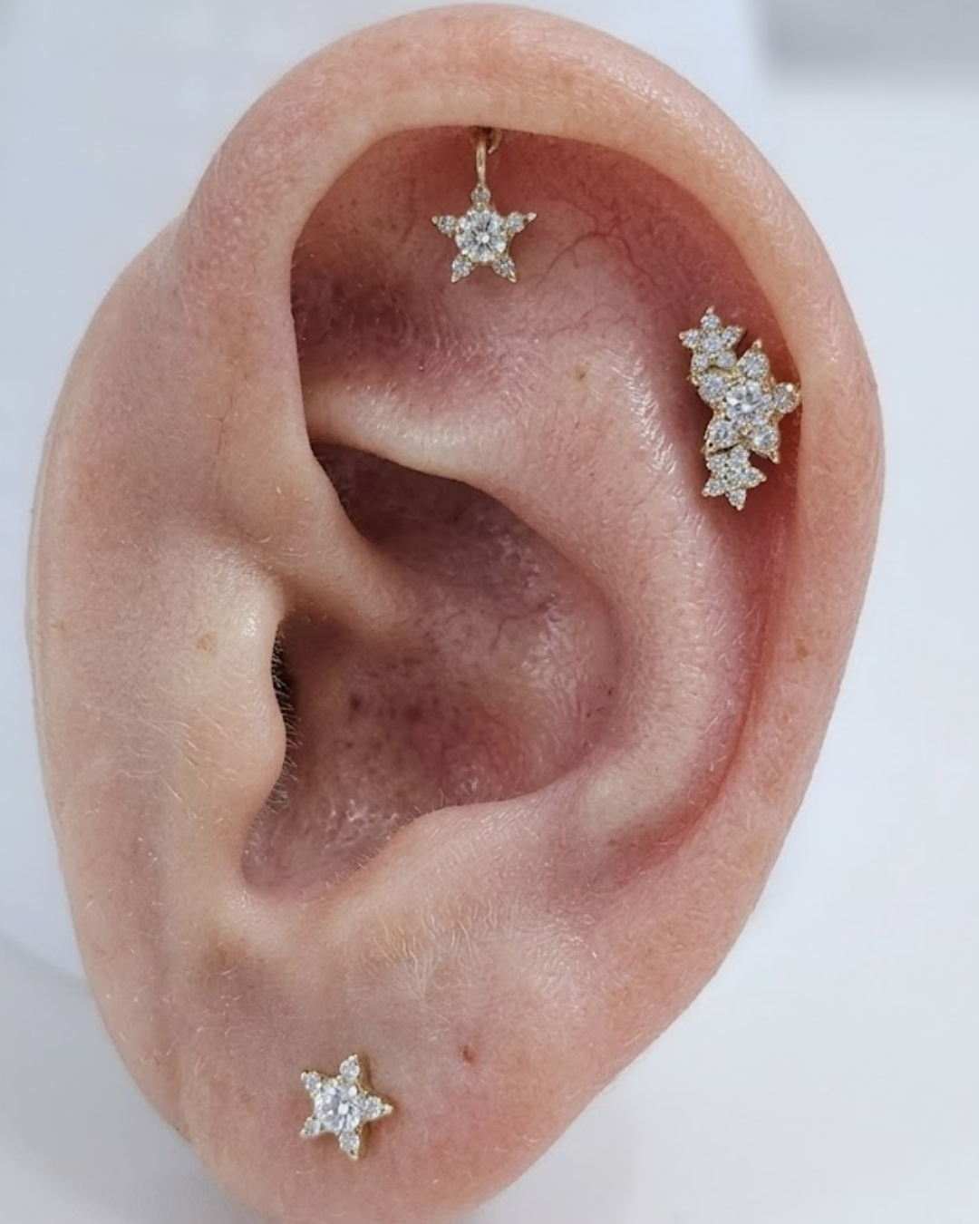 Gold star-shaped earring with clear Moissanite gemstone on a white background by Vai Ra for helix piercing