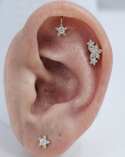 Gold star-shaped earring with clear Moissanite gemstone on a white background by Vai Ra for helix piercing